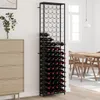 A tall, black wine rack filled with wine bottles stands next to a light-colored dresser in a room with wooden furniture and a window in the background. Anteprima dell’immagine prodotto