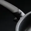 A close-up shot of the handle and rim of a black frying pan. Produktbild-Vorschau