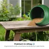 A green barrel spilling granular material onto a wooden table in an outdoor setting. Produktbild-Vorschau