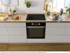 A modern kitchen counter with a built-in oven and induction hob, featuring various kitchenware and ingredients. Produktbild-Vorschau