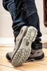 A close-up shot of a person wearing safety sandals and jeans. Produktbild-Vorschau