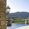 A classic outdoor wall lamp is mounted on a stone pillar, overlooking a serene lake and distant mountains. Produktbild-Vorschau