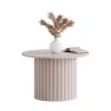 A round coffee table with a fluted base, topped with a white vase containing dried pampas grass and an open book. Produktbild-Vorschau