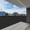 A balcony with a dark gray privacy screen installed along the railing, overlooking a mountainous landscape under a cloudy blue sky. Produktbild-Vorschau