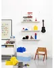 A light blue LEGO snack box is shown on a white background, with other LEGO-themed items and furniture in the scene. Produktbild-Vorschau