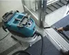 A person is using a teal and white canister vacuum cleaner to clean the floor near a doorway. Produktbild-Vorschau