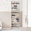 A tall, narrow wooden bookshelf filled with children's books is placed against a wall with a floral wallpaper pattern. A white door with a silver handle is visible to the right. Podgląd zdjęcia produktu