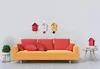 A living room scene with a yellow sofa, red pillows, and three cuckoo clocks on the wall. Anteprima dell’immagine prodotto