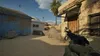 A first-person perspective of a person holding a handgun in a desert-like environment, with another person visible in the background. Produktbild-Vorschau