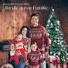 A family in matching Christmas sweaters posing in front of a fireplace and a Christmas tree. Produktbild-Vorschau