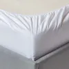 A close-up view of a white fitted sheet on a bed. The sheet has elasticized edges and is pulled taut over the mattress. Produktbild-Vorschau