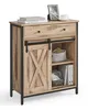 A wooden sideboard with two drawers and a sliding barn door. It is decorated with a framed picture, a cup, and books. Náhled obrázku produktu