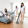 A woman is vacuuming her dog on a couch while another woman vacuums the floor. Náhled obrázku produktu