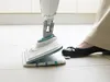 A person is using a steam mop to clean a tiled floor. Voir les images du produit