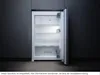 An open refrigerator with its interior light on, set against a dark background. Produktbild-Vorschau