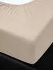 A close-up view of a beige fitted sheet on a black mattress. Produktbild-Vorschau