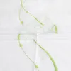 A close-up view of a white sheer curtain with green embroidered wavy lines and small circular embellishments. Produktbild-Vorschau