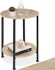 A round, two-tiered side table with a wood-look top and black metal legs, decorated with a plant, a bottle, a glass, and books. Náhled obrázku produktu