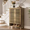 A shoe cabinet with shoes on the bottom shelf, placed next to a staircase in a home. Produktbild-Vorschau