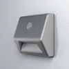 A silver LED battery-powered light fixture with a motion sensor is mounted on a textured white wall. Voir les images du produit