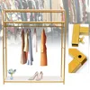 A gold metal clothing rack with several garments hanging on it, and a pair of high heels and a small vase of flowers on the bottom shelf. Insets show close-ups of the rack's construction. Podgląd zdjęcia produktu