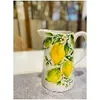 A ceramic pitcher with a lemon and leaf pattern sits on a table. Produktbild-Vorschau
