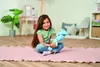 A young girl sits on a pink rug holding a blue plush toy in a room. Náhľad obrázku produktu