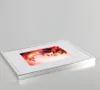 A framed picture of a woman with autumn leaves in her hair, placed on a light gray surface. Produktbild-Vorschau