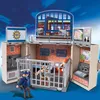 A Playmobil police station playset is shown in an open, unfolded state, with a police officer figure standing guard and a prisoner figure in a cell. Podgląd zdjęcia produktu