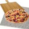 A pizza is shown on a granite pizza stone, with a wooden pizza peel behind it. Podgląd zdjęcia produktu