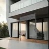 A modern building with a balcony and sliding glass doors leading to a wooden deck. An awning is extended over the deck. Náhled obrázku produktu