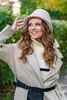 A woman wearing a hat and coat outdoors. Anteprima dell’immagine prodotto