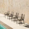 Four chairs are lined up on a tiled patio next to a swimming pool, with a stone wall in the background. Podgląd zdjęcia produktu