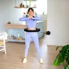 A woman is exercising with a smart hula hoop in a home environment. Náhled obrázku produktu