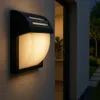 An outdoor wall light mounted on a textured wall next to a doorway. Podgląd zdjęcia produktu