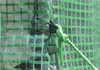 Close-up of a green mesh material with a black clip and a green rope tied to it. Náhled obrázku produktu