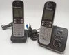 Two Panasonic cordless phones are shown with their charging bases and a power adapter. Voir les images du produit