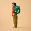 A young child wearing a backpack, shown from the side. Produktbild-Vorschau