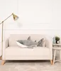 A plush shark toy is placed on a sofa in a room with a lamp and a small table. Podgląd zdjęcia produktu