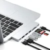 A laptop with a docking station attached, showing various ports and accessories like USB drives and memory cards. Produktbild-Vorschau