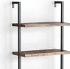 A close-up view of a modern, industrial-style bookshelf with two wooden shelves mounted on black metal supports against a white wall. Náhled obrázku produktu