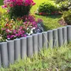A garden border made of gray palisades separates a flower bed from a lawn. Produktbild-Vorschau
