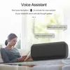 A woman is sitting on a couch reading a book while a portable speaker is on a glass table in front of her. Speech bubbles indicate voice assistant interaction. Produktbild-Vorschau