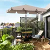 A balcony furnished with plants, a chair, and a large umbrella, overlooking a town. Produktbild-Vorschau