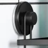 Close-up of a black metal shower shelf attached to a tiled wall with a suction cup. Náhled obrázku produktu