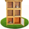 A multi-level wooden rabbit hutch with wire mesh doors, placed on a circular patch of green grass. Podgląd zdjęcia produktu