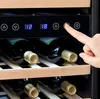A close-up shot of a wine cooler with bottles inside, and a hand pressing a button on the control panel. Produktbild-Vorschau