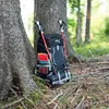 A backpack and hiking poles leaning against a tree in a forest. Anteprima dell’immagine prodotto