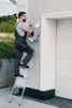 A man is on a ladder painting or cleaning near a garage door. Voir les images du produit