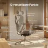 An ergonomic office chair is shown in a well-lit room with a wooden floor and a shelf in the background. The chair has various adjustable features highlighted with text labels. Produktbild-Vorschau
